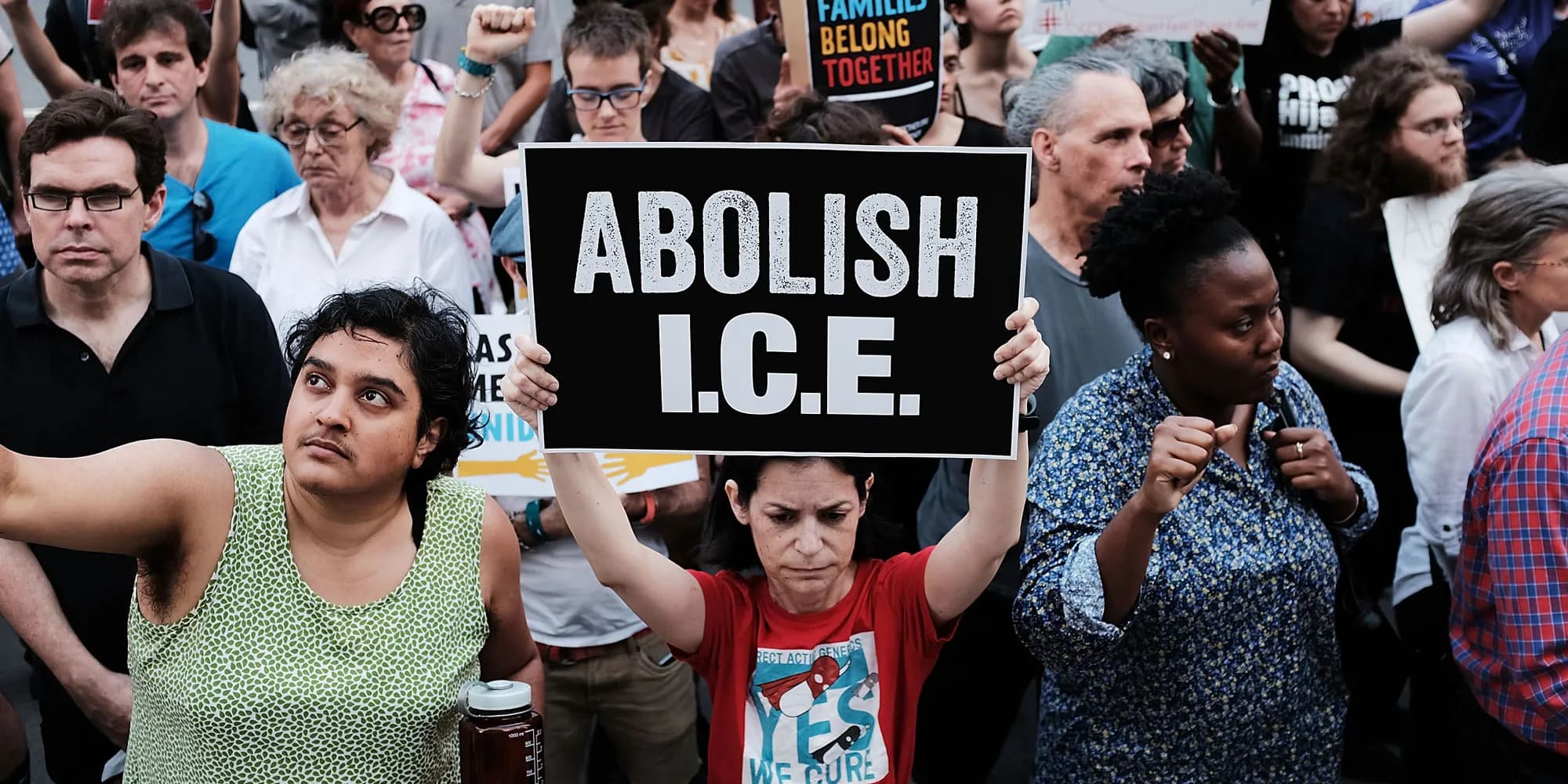 Crowd raising an 'Abolish I.C.E.' sign in a densely packed protest.