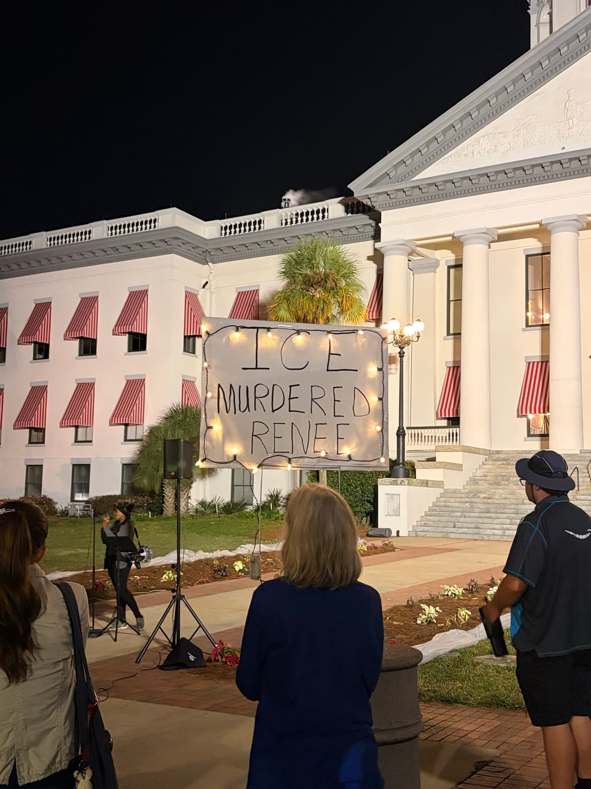 Candlelit vigil at the Florida State Capitol with a hand-lettered sign reading 'ICE murdered Renee.'